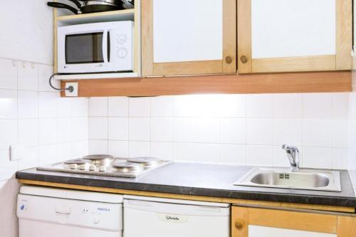 une cuisine avec un évier et un micro-ondes dans l'établissement Quartier La Forêt - maeva Home - Studio 4 Personnes Confort MAE-4163, à Valmorel