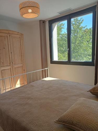 une chambre avec un grand lit et une fenêtre dans l'établissement Maison individuelle plein centre avec jardin ,au pied du Mont Ventoux, à Malaucène