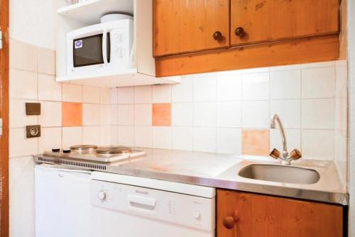 une cuisine avec un évier et un micro-ondes dans l'établissement Quartier La Forêt - maeva Home - Studio 3 Personnes Confort MAE-4169, à Valmorel