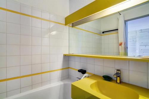 La salle de bains est pourvue d'une baignoire jaune et d'un lavabo jaune. dans l'établissement Résidence Le Hameau du Sauget - maeva Home - 2 Pièces 4 Personnes Confort MAE-4185, à La Plagne Tarentaise