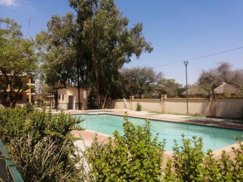 a swimming pool in a yard with trees at Gae La Rona Self Catering Apartment in Gaborone
