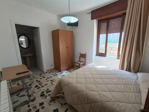 a bedroom with a bed and a desk and a window at VillaTresa in CastellʼUmberto