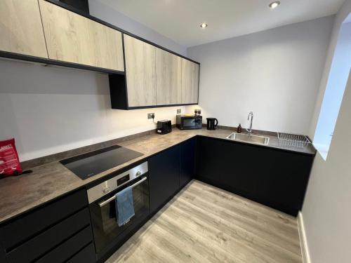 a kitchen with black and white cabinets and a sink at Queen Apartment - High Spec - En-Suites - 7 Guests in Abingdon