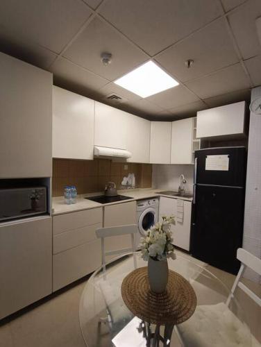 a kitchen with a glass table with a vase of flowers at Modern Studio Oasis - Skyline Views, Private Balcony & Workspace in Ajman