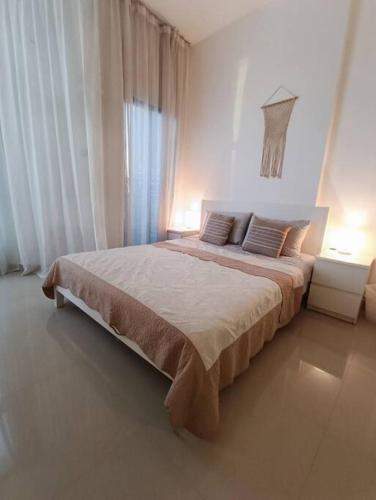 a white bedroom with a large bed with two lamps at Modern Studio Oasis - Skyline Views, Private Balcony & Workspace in Ajman