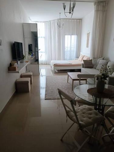 a white living room with a couch and a table at Modern Studio Oasis - Skyline Views, Private Balcony & Workspace in Ajman