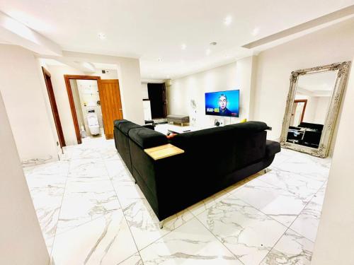 a living room with a black couch and a mirror at Spacious One Bed Property in Wembley in London