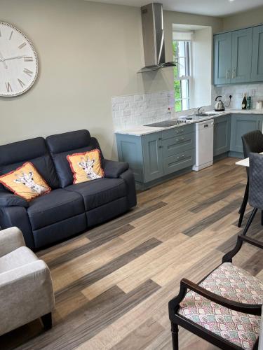 a living room with a black couch and a kitchen at Old Post Office in Linsfort