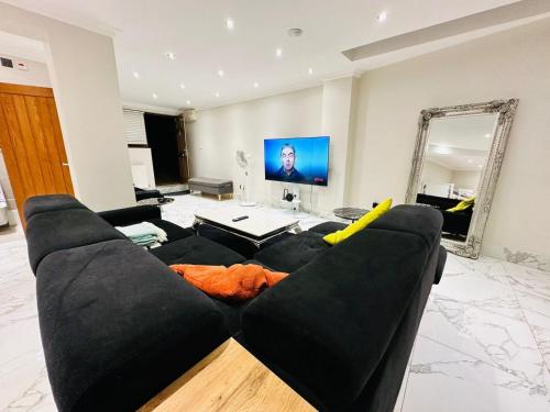 a living room with a black couch and a mirror at Spacious One Bed Property in Wembley in London