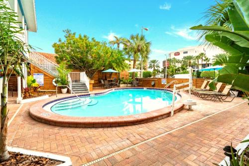 a large swimming pool with a brick walkway around it at Boutique Beach Retreat in St Pete Beach