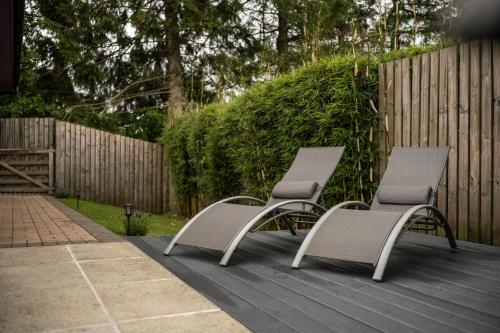 two chairs sitting on a deck next to a fence at The Retreat Cabin in Pitlochry