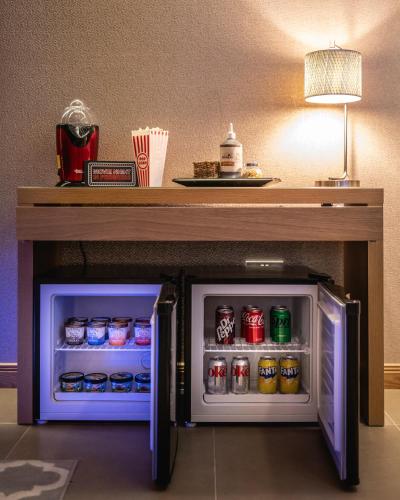 a small refrigerator under a table with soda cans at The Retreat Cabin in Pitlochry