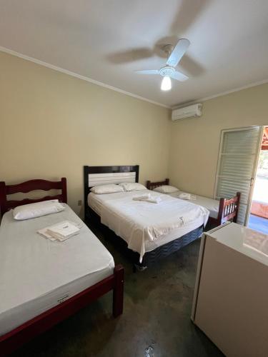 a room with two beds and a ceiling fan at Pousada Keluz in Olímpia