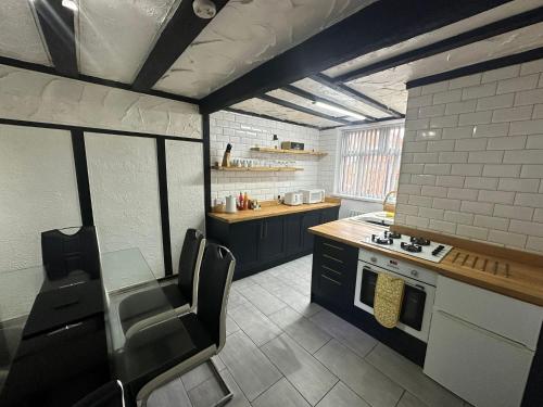 a kitchen with black cabinets and a table and chairs at Modern Pink Cottage in Blackpool in Blackpool