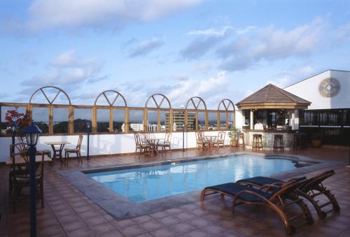 a pool on the roof of a building with tables and chairs at Royal Court Hotel in Mombasa