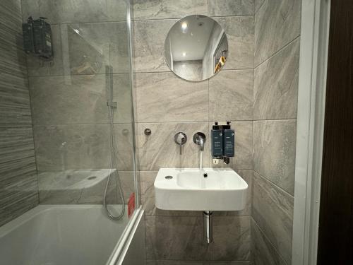 a bathroom with a sink and a tub and a mirror at Luxury 6-Bed House - 6 En Suite- Jaquzzi Baths - Private Parking - Sleeps 22- 2 Min M62 in Elland