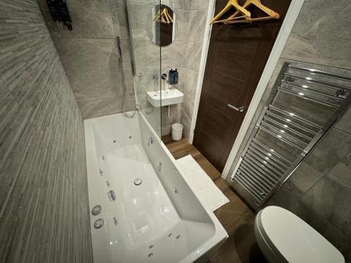 a bathroom with a tub and a toilet and a sink at Luxury 6-Bed House - 6 En Suite- Jaquzzi Baths - Private Parking - Sleeps 22- 2 Min M62 in Elland