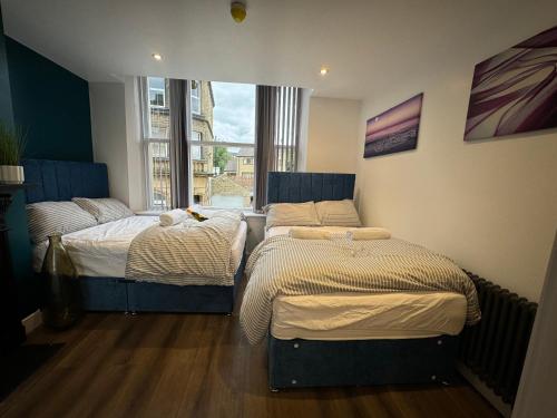 two twin beds in a room with a window at Luxury 6-Bed House - 6 En Suite- Jaquzzi Baths - Private Parking - Sleeps 22- 2 Min M62 in Elland
