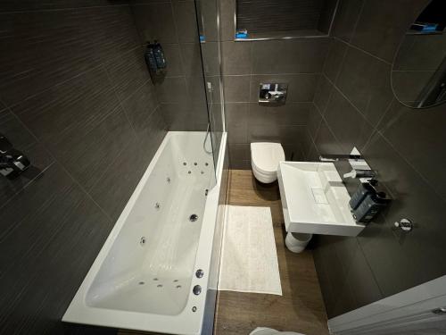 a bathroom with a tub and a sink and a toilet at Luxury 6-Bed House - 6 En Suite- Jaquzzi Baths - Private Parking - Sleeps 22- 2 Min M62 in Elland