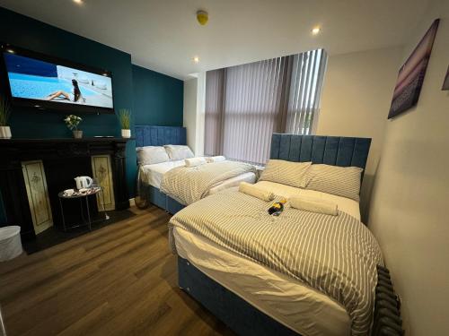 a bedroom with two beds and a flat screen tv at Luxury 6-Bed House - 6 En Suite- Jaquzzi Baths - Private Parking - Sleeps 22- 2 Min M62 in Elland
