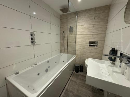a white bathroom with a tub and two sinks at Luxury 6-Bed House - 6 En Suite- Jaquzzi Baths - Private Parking - Sleeps 22- 2 Min M62 in Elland