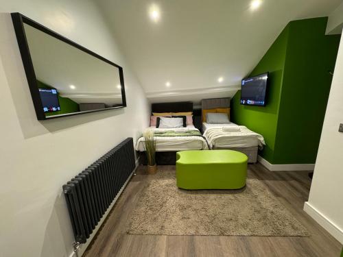 a room with two beds and a green wall at Luxury 6-Bed House - 6 En Suite- Jaquzzi Baths - Private Parking - Sleeps 22- 2 Min M62 in Elland