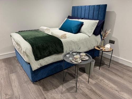 a bed with a blue headboard and a table at Luxury 6-Bed House - 6 En Suite- Jaquzzi Baths - Private Parking - Sleeps 22- 2 Min M62 in Elland