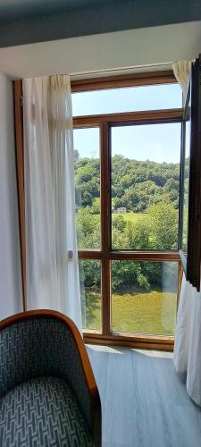 a bedroom with a large window with a bed and a chair at Hotel Ciudad Cangas de Onis in Cangas de Onís