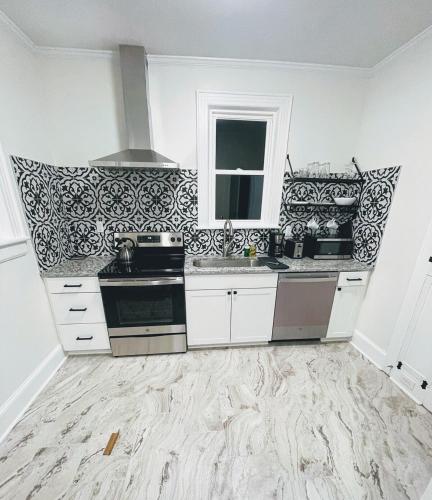 a kitchen with white cabinets and black and white wallpaper at Renovated 1 bedroom in Forest Hills - B in Durham