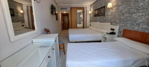 a hotel room with two beds and a mirror at Hotel Ciudad Cangas de Onis in Cangas de Onís