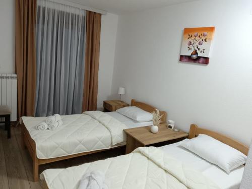 a hotel room with two beds and a table at Apartmani Smiljković90 in Aleksandrovac
