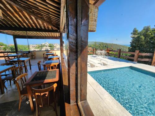 a pool with tables and chairs next to a restaurant at Pousada Dreamland Buzios in Búzios