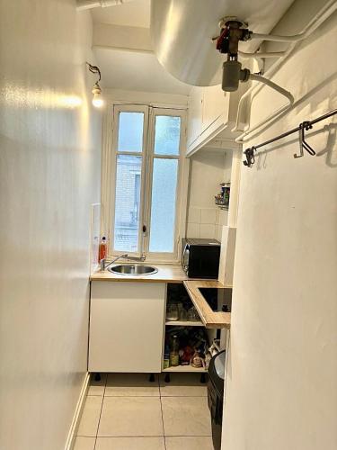 une petite cuisine avec un évier et une fenêtre dans l'établissement Guest House Tour Eiffel Paris, à Paris