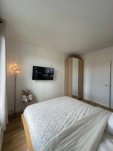 une chambre avec un lit et une télévision au mur dans l'établissement Superbe appartement lumineux et cosy proche Paris, à Villemomble