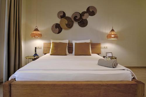 a bedroom with a large white bed with brown pillows at La Maison Vanille in Ngaparou