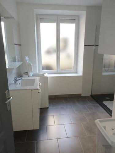 une salle de bain avec deux lavabos et une fenêtre dans l'établissement Appartement en rez-de-chaussée, à Fourchambault
