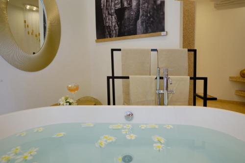 a bathroom with a tub with a mirror and chairs at La Maison Vanille in Ngaparou
