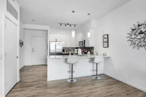 a white kitchen with a counter and two stools at Urban Chic 1BR Downtown Tampa Pool & Balcony Views in Tampa