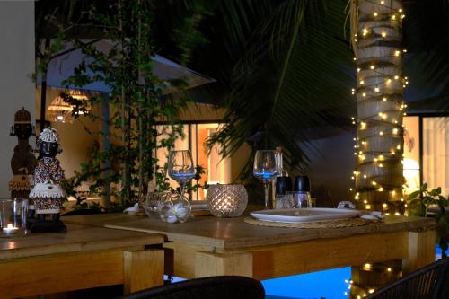 a wooden table with wine glasses and lights on it at La Maison Vanille in Ngaparou