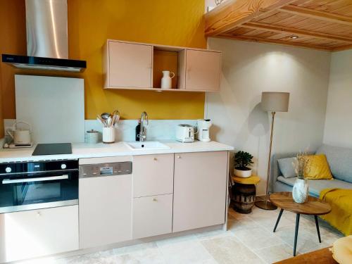 une cuisine avec des armoires blanches, une table et un canapé dans l'établissement Le petit Cocon du Lac, à Lacanau