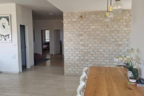 a dining room with a table and a brick wall at וילה במושב בנוף מושלם כל השנה in Moledet