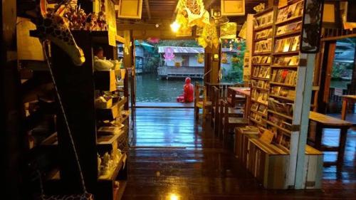 une femme assise dans une librairie avec une pièce remplie de livres dans l'établissement Longtail Boat Tour bangkok Tour Klong, à Chinatown