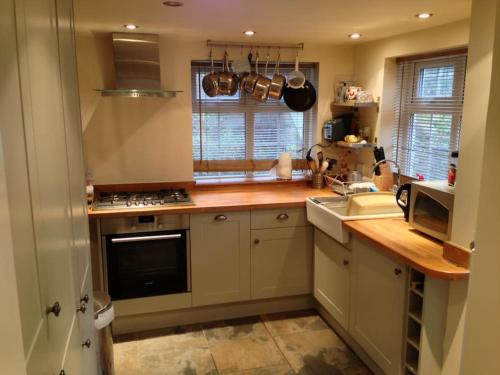 a kitchen with a wooden counter top and a sink at Thatch End Cottage in Baslow