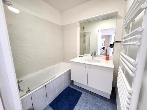 La salle de bains blanche est pourvue d'une baignoire, d'un lavabo et d'un miroir. dans l'établissement Cozy apartment, Balcon, Parking, 5' Disneyland, à Montévrain