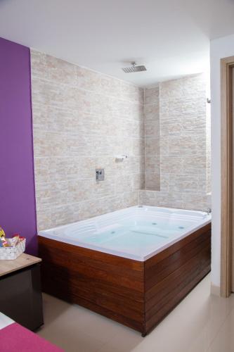 a large bath tub in a room with a brick wall at Bajo la luna hotel in Medellín