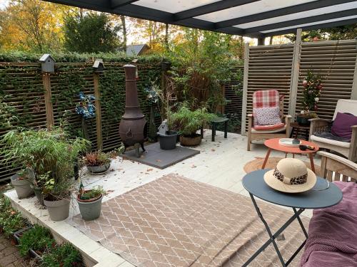 a garden with a patio with plants and a heater at Gezellige ruime Cottage, privé, 2 slaapkamers, hond welkom! in Hattemerbroek