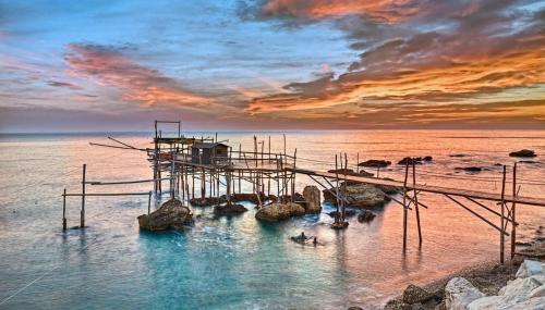 a dock in the water with a sunset at Relax Apartment in San Salvo