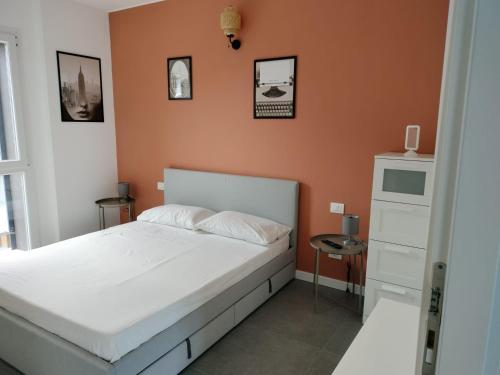 a bedroom with a white bed and an orange wall at Relax Apartment in San Salvo