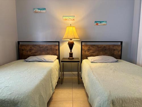 two beds in a room with a lamp on a table at Coastal Breeze - 2BR Apartment in West Palm Beach