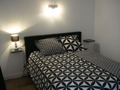 - une chambre avec un lit noir et blanc et des oreillers dans l'établissement L'appartement du Lys, à Périgueux
